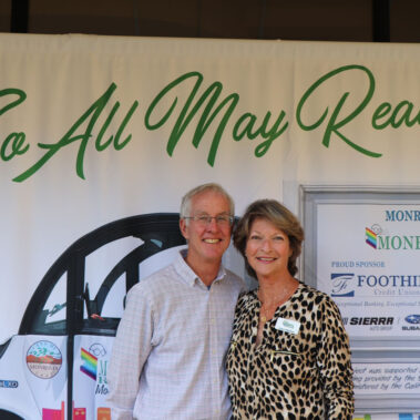 Joann and John Wallace posing in front of banner