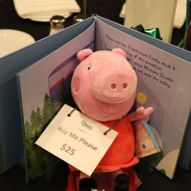 A stuff Peppa the pig animal and book for sale as a center piece on a table.