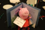 A stuff Peppa the pig animal and book for sale as a center piece on a table.