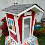 Little Library that looks like a doll house colored in red and white.