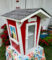 Little Library that looks like a doll house colored in red and white.