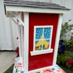Little Library that looks like a doll house colored in red and white side view.