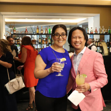 Woman and a man hold drinks with a smile to cheer.